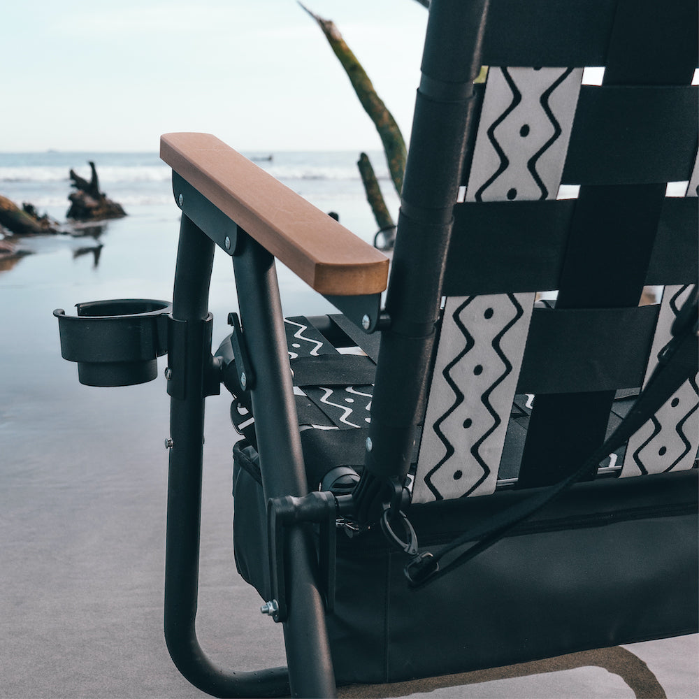 Black and white patterned chair with wooden armrest on a beach