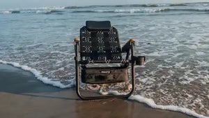 Foldable chair on a sandy beach with ocean waves in the background