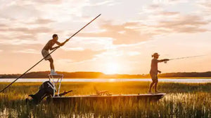 Two people on paddle boats with sunset in the background
